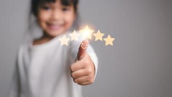 menina bonitinha dando polegares para cima com 5 estrelas aprovadas foto