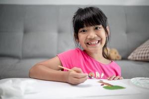 menina pintando quadro na mesa em casa foto