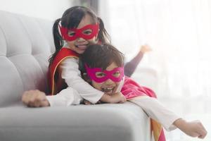 crianças felizes e confiantes brincando e se vestindo como super-heróis juntos no quarto foto