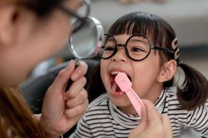 linda criança asiática brincando com conjunto de brinquedos médico dentista, criança mostra como limpar e cuidar dos dentes. odontologia e medicina, foto