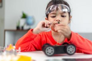 os alunos da ásia aprendem em casa na codificação de carros robóticos e cabos de placa eletrônica em haste, vapor, código de computador de tecnologia de ciência de engenharia matemática em robótica para o conceito de crianças. foto