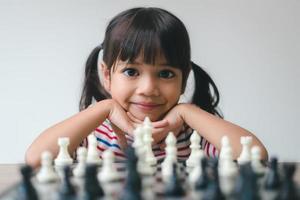 menina asiática jogando xadrez em casa. um jogo de xadrez foto