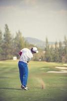 os jogadores de golfe atingem o campo de golfe arrebatador no verão.cor vintage foto