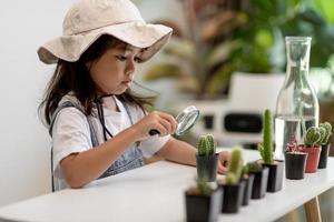 menina asiática está plantando plantas em casa, conceito de atividade de aprendizado de crescimento de plantas para uma criança pré-escolar e educação infantil para a árvore na natureza foto