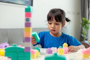 adorável menina jogando blocos de brinquedo em uma sala iluminada foto