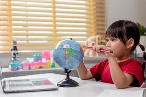 menina asiática está aprendendo o modelo do globo, o conceito de salvar o mundo e aprender através da atividade lúdica para a educação infantil em casa. foto