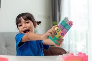 adorável menina jogando blocos de brinquedo em uma sala iluminada foto