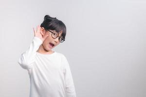 menina asiática segura a mão perto da orelha e escuta. deficiência day.deaf kid. rosto emocionante na menina criança asiática. desligue o telefone e ouça seu filho. foto