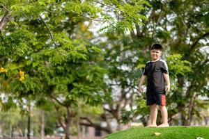 criança brincando no playground ao ar livre. as crianças brincam na escola ou no jardim de infância. criança ativa no escorregador colorido e balanço. atividade de verão saudável para crianças. menino escalando ao ar livre. foto