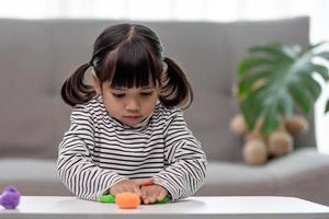 a menina está aprendendo a usar massinha colorida em uma sala bem iluminada foto