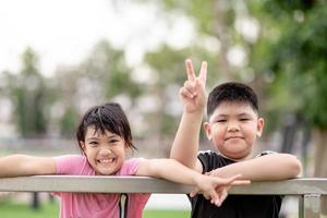 duas crianças asiáticas menino e menina felizes e sorriam no parque foto
