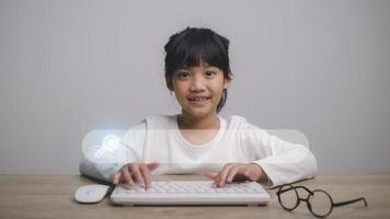 crianças inteligentes, otimização de mecanismo de pesquisa de tecnologia de pesquisa de dados. mãos de linda garota estão usando um teclado de mouse e computador para procurar informações. usando o console de pesquisa com seu site. foto