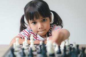 menina asiática jogando xadrez em casa. um jogo de xadrez foto