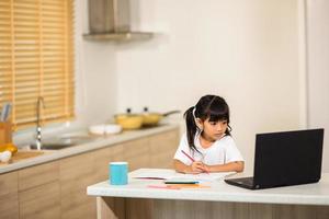 surto de coronavírus. confinamento e fechamento de escolas. colegial assistindo aula de educação on-line, feliz conversando com o professor na internet em casa. pandemia de covid-19 força crianças a aprender online foto