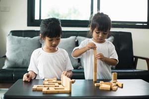 dois irmãos felizes jogando um jogo com blocos de madeira em casa com alegria foto