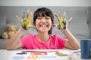 conceito de educação, escola, arte e painitng - garotinha estudante mostrando as mãos pintadas foto