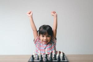 menina asiática jogando xadrez em casa. um jogo de xadrez foto