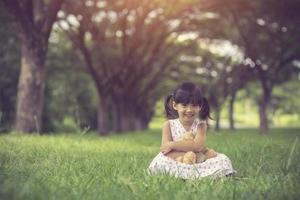 menina abraçando seu ursinho de pelúcia no parque.cor vintage foto