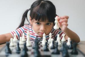 menina asiática jogando xadrez em casa. um jogo de xadrez foto