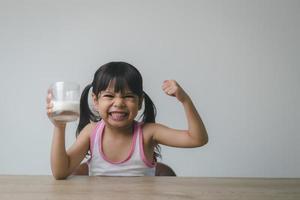 menina asiática está bebendo leite de um copo ela estava muito feliz. foto