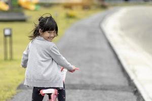 menina criança alegre feliz andando de bicicleta no parque na natureza foto