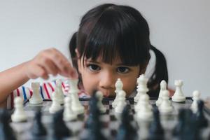 menina asiática jogando xadrez em casa. um jogo de xadrez foto