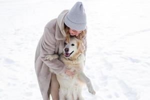 jovem mulher bonita e seu cachorro retriever dourado se divertindo no inverno. foto