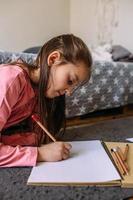 a garota depois da escola brinca em casa, desenha com lápis e canetas hidrográficas foto