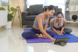 ajuste mulheres jovens amigas praticando ioga em casa via aula on-line com instrutor profissional, esporte e conceito de estilo de vida saudável. foto