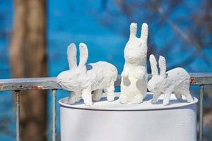 três estátuas de coelho branco feitas de gesso no barril na exposição de arte ao ar livre, lebres artificiais foto