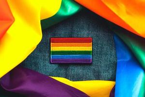 close-up de patch têxtil de bandeira lgtbi em uma jaqueta jeans e bandeira lgtbi. conceito de dia do orgulho foto