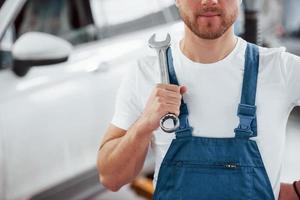 homem sem barba. funcionário de uniforme de cor azul trabalha no salão de automóveis foto