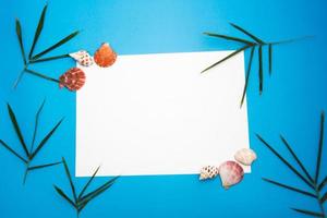 conceito de papel em branco para texto com molduras adornadas com folhas de bambu, concha e fundo de papel azul. foto