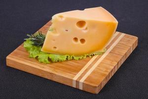queijo maasdam no tabuleiro servido com folhas de salada foto