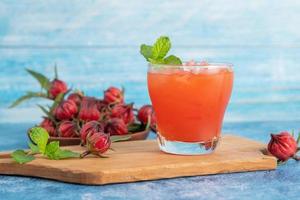 copo de chá de roselle gelado com frutas frescas de roselle na mesa de madeira para o conceito de bebida de ervas saudável. chá orgânico de ervas para uma boa saúde. foto