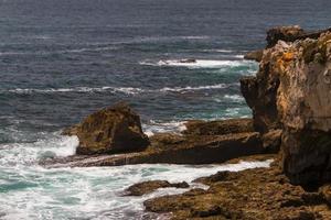 as ondas lutando sobre a costa rochosa deserta do oceano atlântico, portugal foto