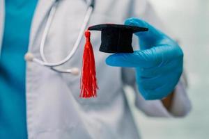 estudo de médico asiático aprende com chapéu de graduação na enfermaria do hospital, conceito de medicina de educação de gênio brilhante inteligente. foto