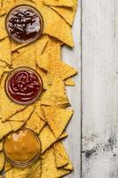 nacho chips mexicanos e mergulho colorido na borda de taças de vidro