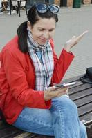 foto de uma mulher sorridente satisfeita segurando um telefone celular e movendo a mão para o lado. uma menina, uma jovem fica surpresa ao ler uma mensagem em um smartphone.