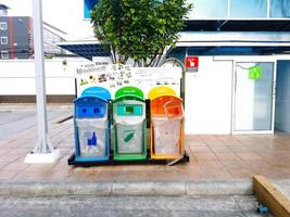 bangkok, tailândia - 27 de agosto de 2017 colorido de três lixeiras ou lixo para coleta de material na calçada em frente ao banheiro com deficiência. conceito de cidade limpa, mundo verde e redução de material foto