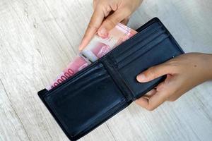 mão segurando a carteira com dinheiro foto