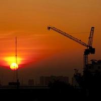 guindaste no canteiro de obras ao pôr do sol foto