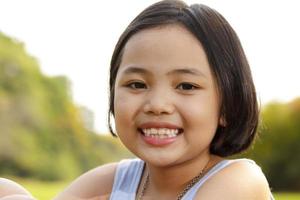 menina asiática sorrindo alegremente no parque foto