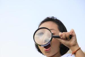 menina asiática segurando uma lupa ao ar livre foto