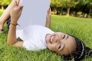 menina asiática relaxar e ler um livro no parque foto