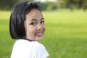 menina asiática relaxa e sorrindo alegremente no parque foto