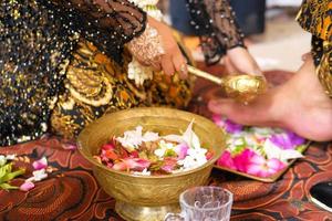 noiva javanesa tradicional, o processo de limpeza dos pés do marido com flores para noivas javanesas foto