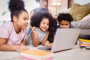feliz família afro-americana estudando online pelo computador portátil em casa foto