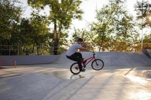 bmx rider treinando e fazendo truques na street plaza, bicyxle stunt rider em coccrete skatepark foto