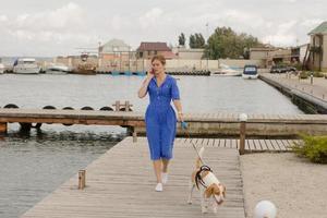 jovem mulher de vestido azul tendo tempo com cachorro beagle foto